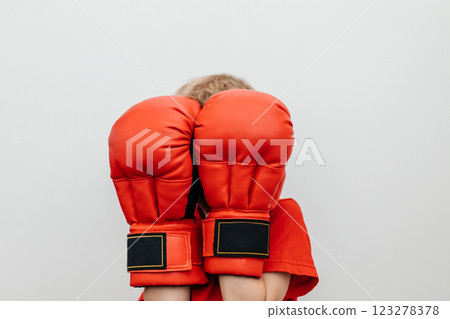 Boy covers his face with boxing gloves. Block, protection. Banner. Place for the text Boy covers his face with boxing gloves. Block, protection. Banner. Place for the text 123278378
