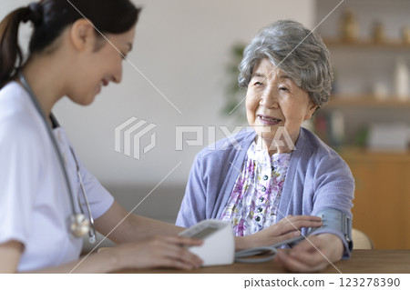 Senior woman having her blood pressure measured by a nurse 123278390