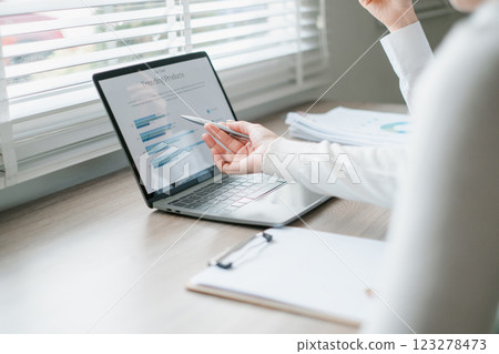 Business professional analyzing financial data on a laptop in a bright office setting with documents and natural light. Business professional analyzing financial data on a laptop in a bright office setting with documents and natural light. 123278473