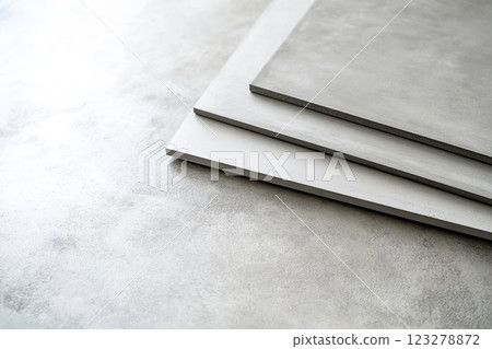 Close up of fiber cement boards displaying their texture and edges, stacked on a concrete surface 123278872