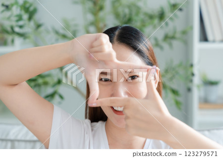 Young asian woman happy and making frame with fingers at living room 123279571