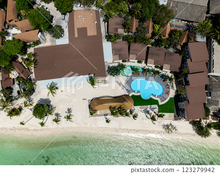 An aerial view of a resort with a pool and rows of palm trees along a white sandy beach and turquoise sea. Rin Nai Beach. Ko Pha Ngan, Thailand. 123279942