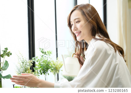 A woman enjoying gardening while watering plants A woman enjoying gardening while watering plants 123280165