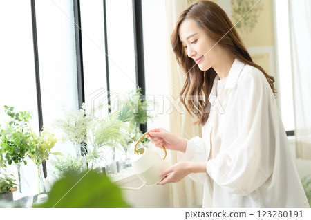 A woman enjoying gardening while watering plants 123280191