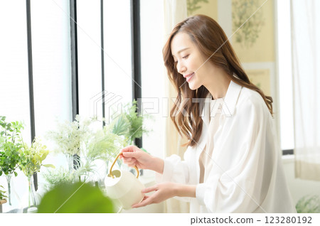 A woman enjoying gardening while watering plants A woman enjoying gardening while watering plants 123280192