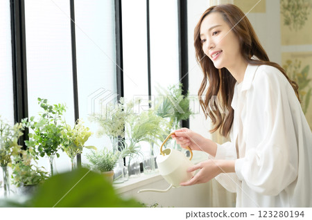 A woman enjoying gardening while watering plants A woman enjoying gardening while watering plants 123280194