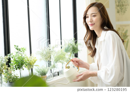 一位女士一邊澆水一邊享受園藝樂趣 123280195