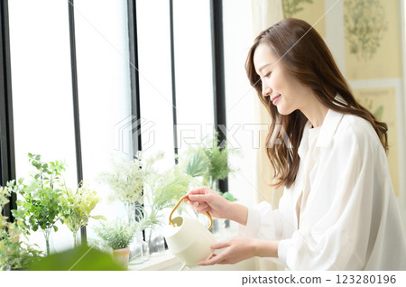 一位女士一邊澆水一邊享受園藝樂趣 123280196