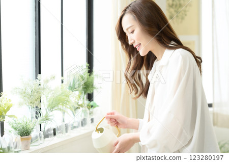 一位女士一邊澆水一邊享受園藝樂趣 123280197