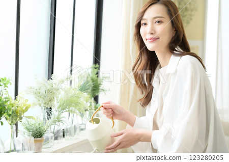 A woman enjoying gardening while watering plants A woman enjoying gardening while watering plants 123280205