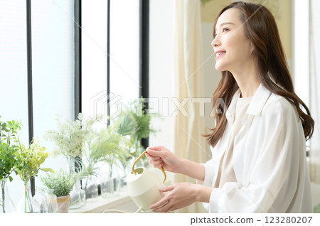 A woman enjoying gardening while watering plants A woman enjoying gardening while watering plants 123280207