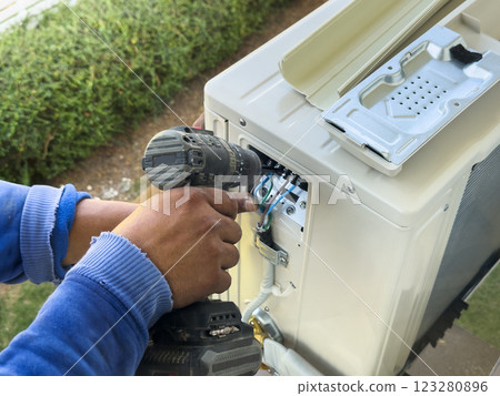 worker connects electric wires to installation of air conditioner 123280896