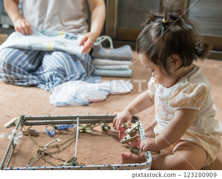 [Baby with twin tails touching a laundry hanger] 123280909