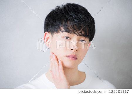 A young man in his 20s touching his cheek and looking at the camera. Beauty and beauty image A young man in his 20s touching his cheek and looking at the camera. Beauty and beauty image 123281317