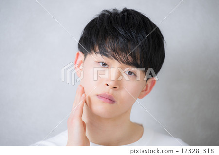 A young man in his 20s touching his cheek and looking at the camera. Beauty and beauty image 123281318
