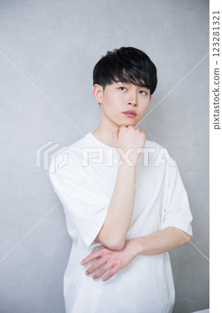 A young man in his 20s with his hand on his chin and looking at the camera. Beauty and beauty image. Serious and serious expression. 123281321