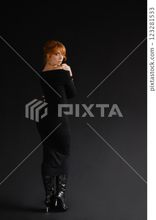 Elegant woman with red hair in black off-the-shoulder dress on dark background Elegant woman with red hair in black off-the-shoulder dress on dark background 123281533