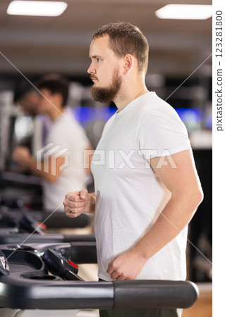 Focused bearded man works out with treadmill during class at fitness club 123281800