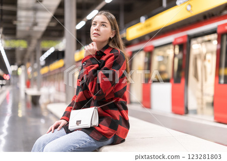 Girl is sitting on subway platform, waiting for train to arrive 123281803