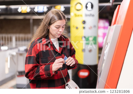 Girl buys travel ticket from machine at subway stop 123281806