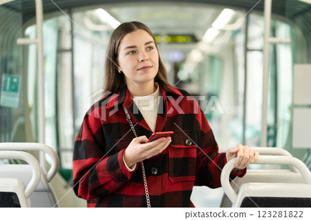 Girl is standing with phone in tram car, getting to work 123281822