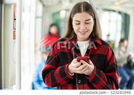 Girl with long hair standing in tram with phone 123281840