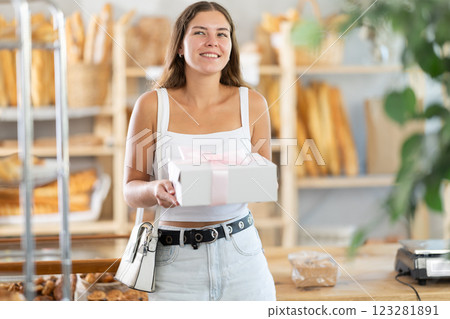 Young woman with pastries in box in bakery Young woman with pastries in box in bakery 123281891