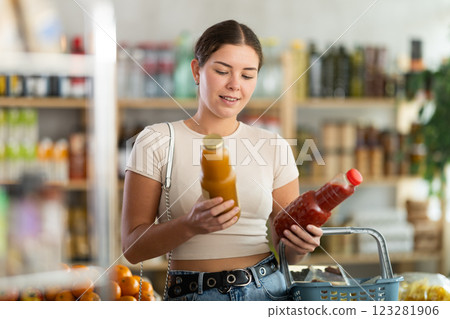 Young woman buyer chooses tomato and peach juices 123281906