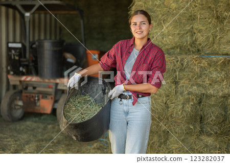 Young woman with bucket of hay in barn Young woman with bucket of hay in barn 123282037