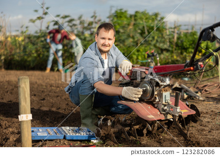 Young man repairing weeding machine Young man repairing weeding machine 123282086