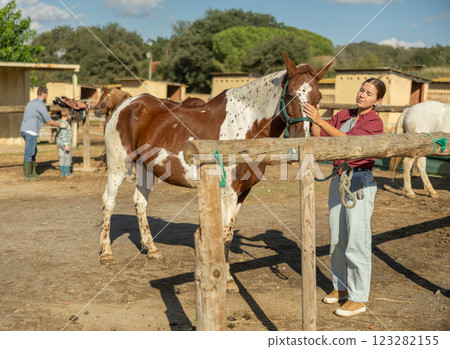 Young woman leads horse to hitching post 123282155