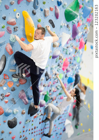 Man climbing a tall, indoor, man made rock climbing wall Man climbing a tall, indoor, man made rock climbing wall 123282163