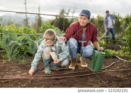 Young woman with boy planting seeds in field 123282191