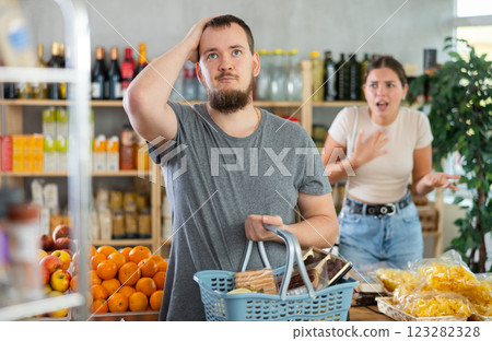 Wife stands behind husband and yells at companion in shop Wife stands behind husband and yells at companion in shop 123282328