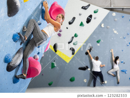 Sportive woman climbing on artificial rock wall in rock climbing gym Sportive woman climbing on artificial rock wall in rock climbing gym 123282333