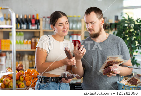 couple scans the QR code of meat products on their phone couple scans the QR code of meat products on their phone 123282360