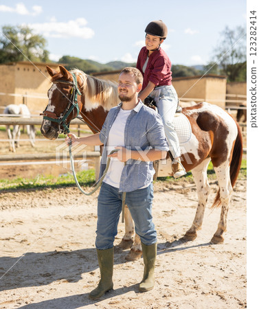 Young man leading horse with woman riding 123282414