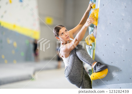 Young woman practicing rock climbing on climbing wall Young woman practicing rock climbing on climbing wall 123282439