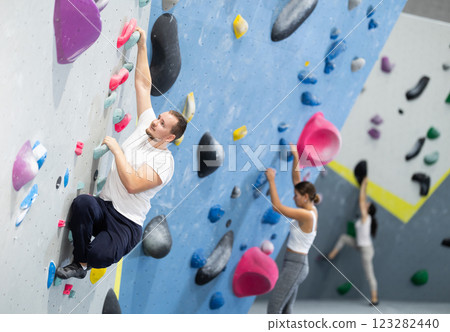 Man climbing a tall, indoor, man made rock climbing wall Man climbing a tall, indoor, man made rock climbing wall 123282440