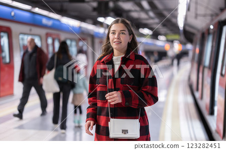 Girl is standing on subway platform, waiting for train to arrive Girl is standing on subway platform, waiting for train to arrive 123282451