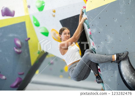 Sportive woman climbing on artificial rock wall in rock climbing gym 123282476