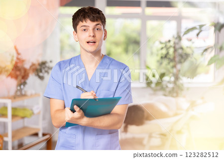 Young guy masseur makes notes in office Young guy masseur makes notes in office 123282512