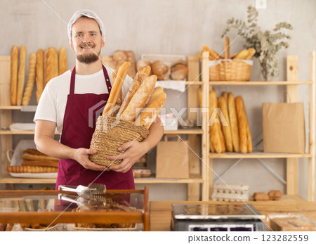 Young male seller with baguettes in basket 123282559