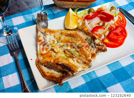 Fried dorada dressed with pesto served with vegetable garnish and lemon Fried dorada dressed with pesto served with vegetable garnish and lemon 123282640