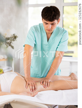 Young guy massages thighs of adult woman 123282676