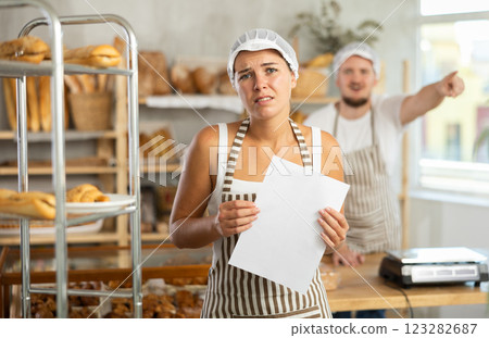 In bakery, confused female employee with documents during quarrel with guy boss In bakery, confused female employee with documents during quarrel with guy boss 123282687