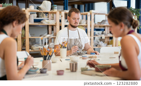 Three craftsperson are busy painting clay products 123282880