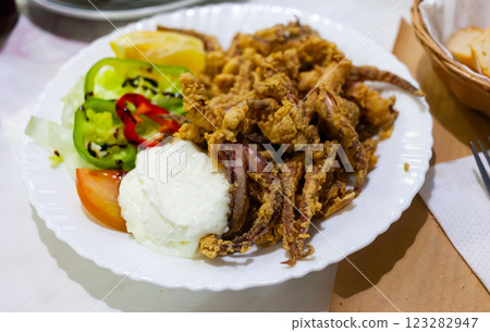 Popular Spanish tapa rejos - fried spicy tentacles of squid served with lemon slice 123282947