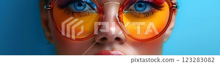 Closeup of woman with amber sunglasses against blue background 123283082