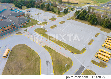 Spacious school parking lot remains vacant in early spring, with yellow school buses lined up nearby 123283800